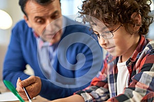 Little learner. Close up portrait of happy little hispanic school boy doing homework together with his father while