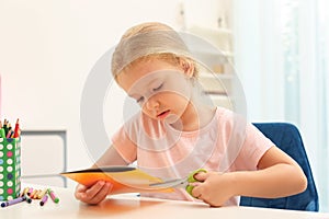 Little left-handed girl cutting construction paper