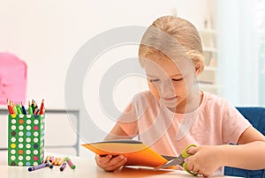 Little left-handed girl cutting construction paper