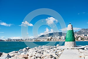 A little lighthouse of white and green color at the pier covered