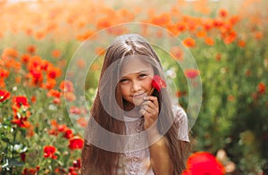 Little longhaired girl  posing at field of poppies with  on summer sun