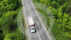 Little lorry driving on the highway, aerial. Green grass and trees on both sides of the road