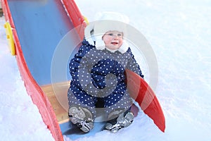 Little lovely baby girl in warm clothes outdoor in winter