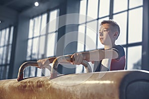 Little male gymnast training in gym, flexible and active