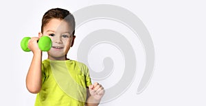 Little male in yellow t-shirt and denim shorts. He smiling, lifting green dumbbell, posing isolated on white studio background