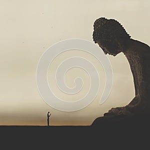 Little man meditates praying in front of a giant buddha photo