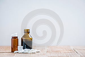 Little medicine bottles and many white tablets on a wooden table