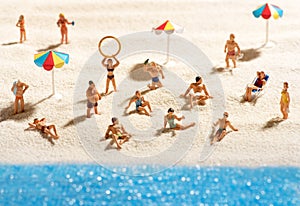 Little miniature people sunbathing on a beach