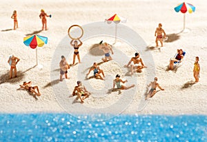 Little miniature people sunbathing on a beach photo