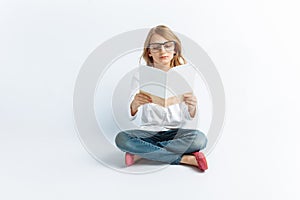 Little modern girl with glasses reading a book and dreaming, on isolated background, cute and beautiful