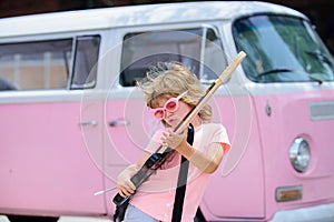 Little musician playing guitar. Fashionable little boy in funny sunglasses. Kids music school concept.