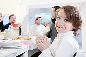 Little muslim boy praying with family before iftar dinner