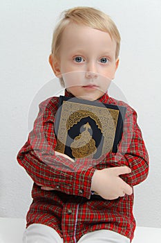 Little muslim European boy with islamic holy book Quran or Kuran photo
