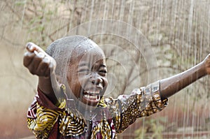 Little Native African Black Boy Standing Outdoors Under the Rain Water for Africa Symbol photo