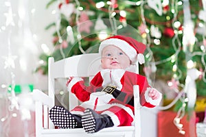 Little newborn baby boy in Santa costume under Christmas tree