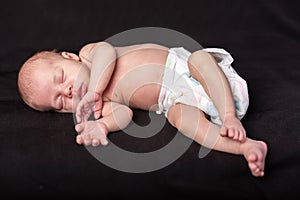 Little newborn baby boy sleeps in darck background