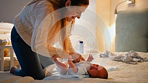 Little newborn baby crying and screaming while mother changing clothes and diapers on bed at night. Concept of baby