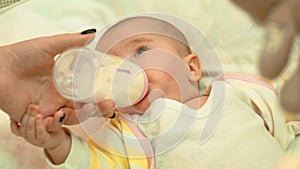 Little newborn baby drinking milk from a bottle