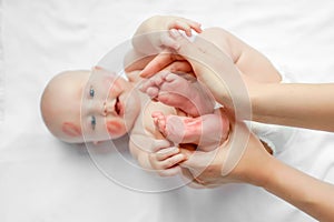 Little newborn baby foot in the hands of mother. adorable child with red kisses on the skin, happy baby on white background. top