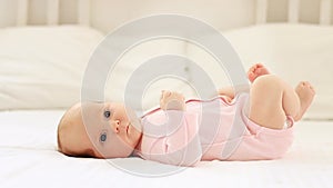 little newborn baby girl lies on a white cotton bed at home