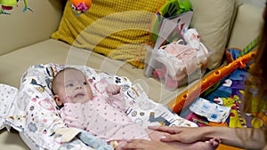 Little newborn girl lies in her crib with toys