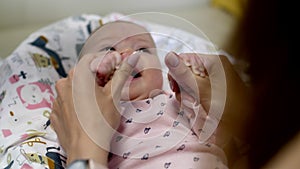 Little newborn girl lies in her crib with toys