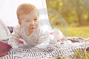 Little newborn infant baby boy kid on a plaid in park. Summer sunset. Copy space