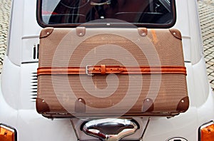 little old car with a vintage suitcase strapped on its back