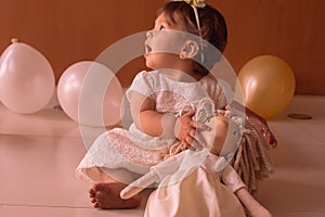 Little one year girl baby with balones and dolly photo