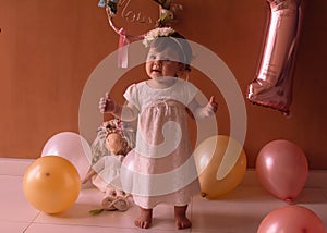 Little one year girl baby with balones and dolly photo