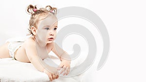 The little one-year-old girl lies on the bed a white background.. Concept of Health and Medicine. copy space
