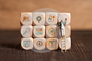 Little painter figure is writing marketing symbols on wooden blocks