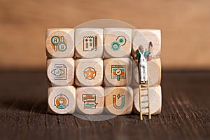 Little painter figure is writing marketing symbols on wooden blocks