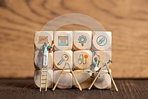 Little painter figure is writing marketing symbols on wooden blocks