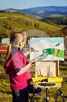 Little painter at work near waterfall