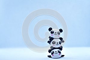 Little panda stacked porcelain figurines isolated on black background