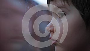 Little passenger looks through window from train. Portrait of a boy looking at freight train through train`s window