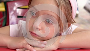 Little pensive girl at a red table