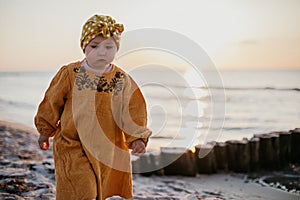 Little pensive girl on sunset beach