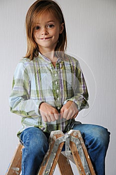 Little perky girl sits on a ladder