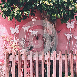 Little pink garden with fence and butterfy. Still life.