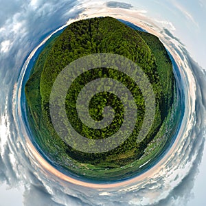 Little planet with dark mountain hills covered with green mixed pine and lush forest