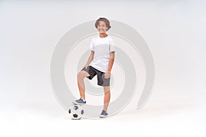 Little player. Full-length shot of a happy teenage boy with soccer ball looking at camera and smiling while standing