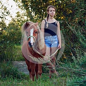 Little pony horse with teenage girl outdoors at countryside
