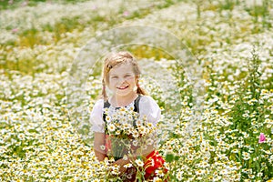 Little preschool girl in daisy flower field. Cute happy child in red riding hood dress play outdoor on blossom flowering