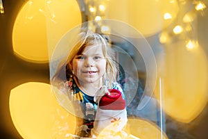 Little preschool girl holding cup Santa Claus boot with gift called Nikolausstiefel in German. Happy child wait on