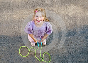 Little preschool girl jump and train with skipping rope. View from above on cute happy active child. Summer sports and