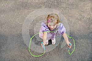 Little preschool girl jump and train with skipping rope. View from above on cute happy active child. Summer sports and