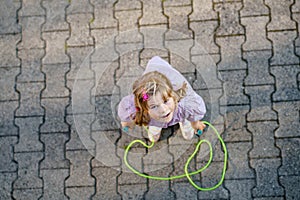 Little preschool girl jump and train with skipping rope. View from above on cute happy active child. Summer sports and