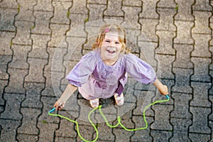 Little preschool girl jump and train with skipping rope. View from above on cute happy active child. Summer sports and